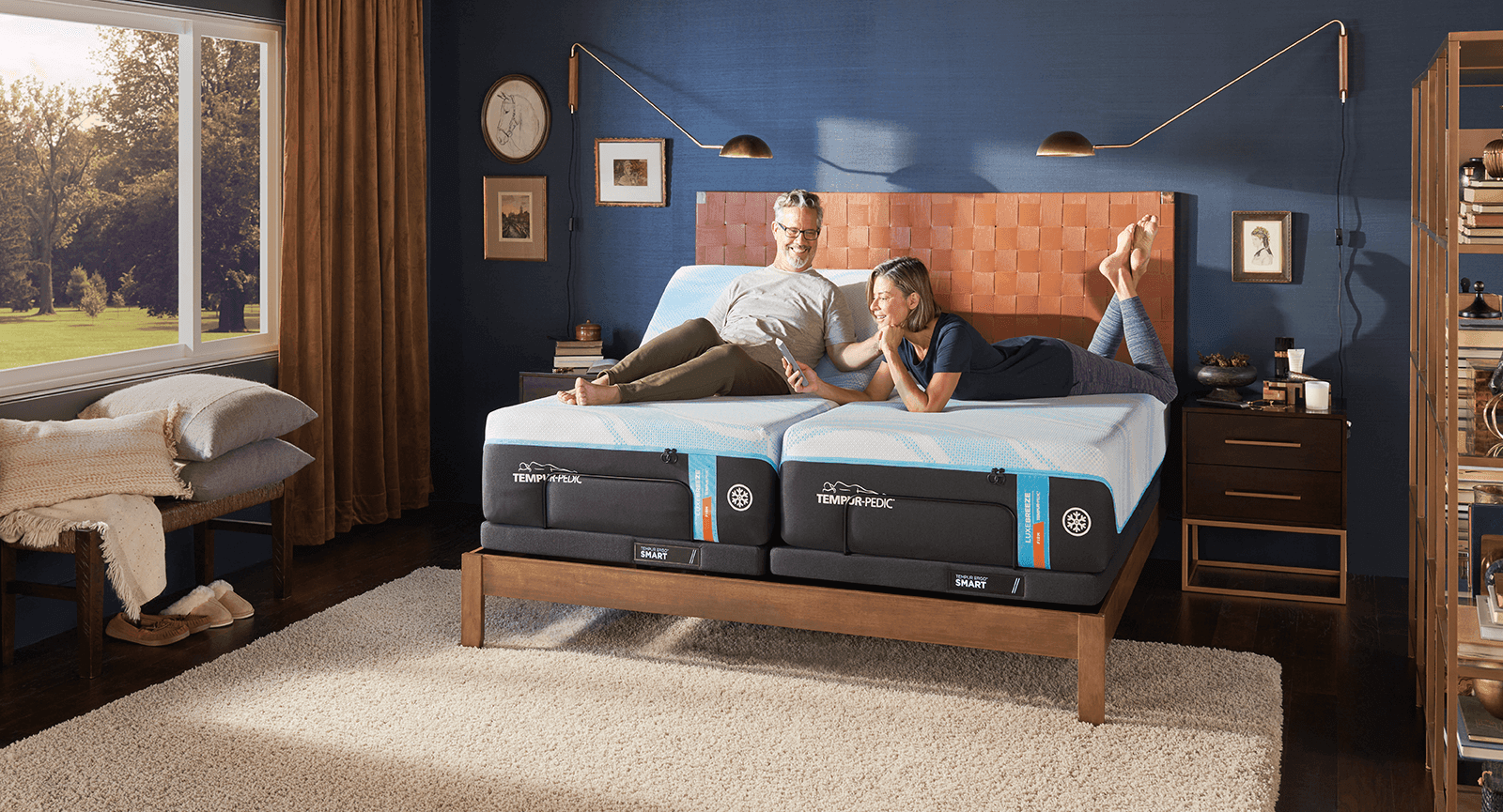 A couple laying on a split king mattress in a decorated room